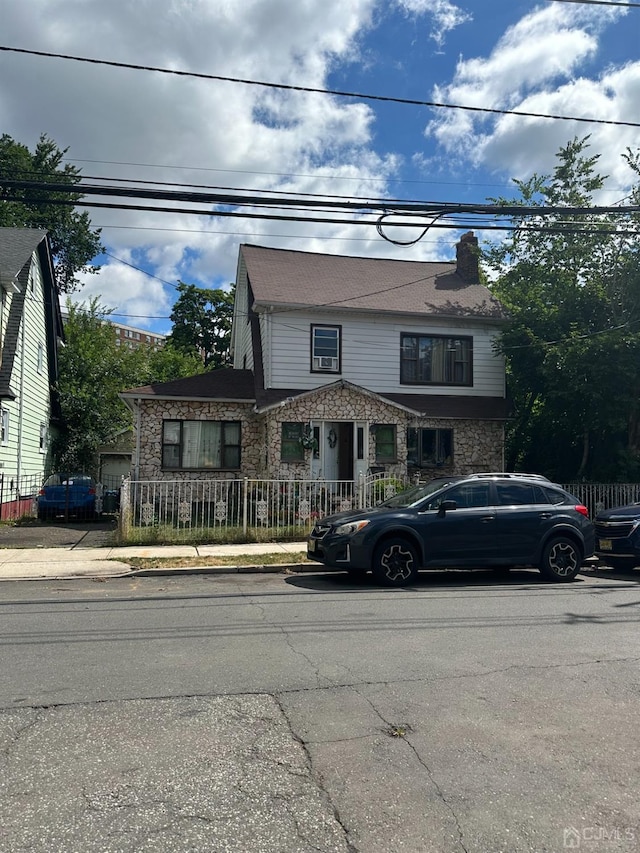 view of front of house with fence, a chimney, and stone siding