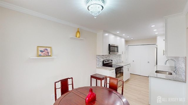 dining space with an inviting chandelier, recessed lighting, light wood-style floors, and ornamental molding