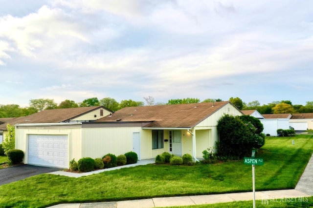 single story home featuring an attached garage, driveway, and a front lawn