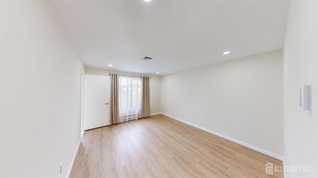 empty room with visible vents, baseboards, light wood-style floors, and a baseboard radiator