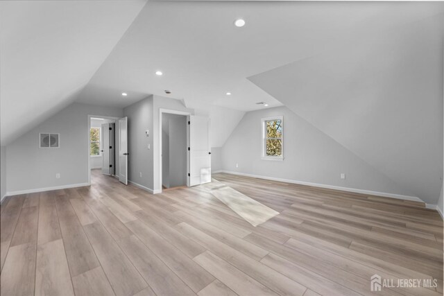 additional living space with light wood-type flooring, a wealth of natural light, and lofted ceiling