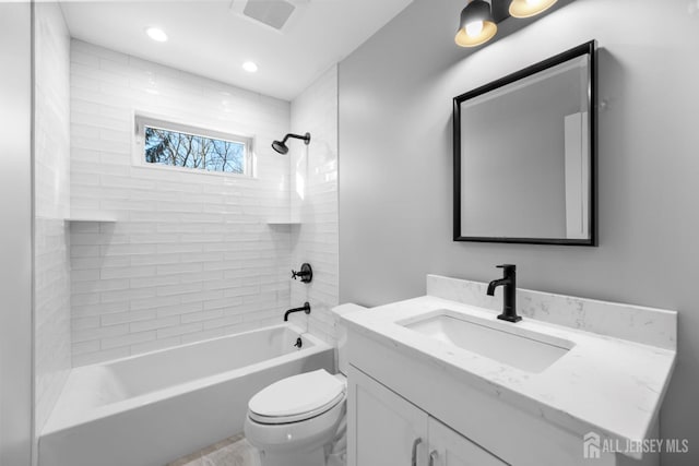 full bathroom featuring vanity, tiled shower / bath combo, and toilet