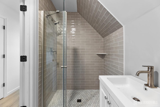 bathroom featuring a shower with door, lofted ceiling, and vanity