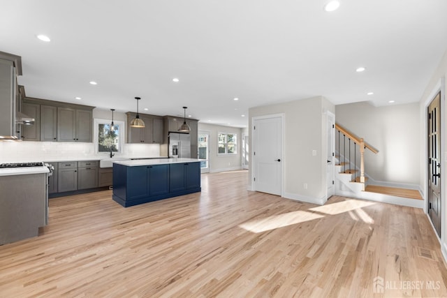 kitchen with pendant lighting, stainless steel fridge, light hardwood / wood-style floors, decorative backsplash, and a kitchen island