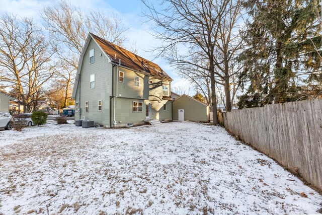 snow covered rear of property featuring cooling unit