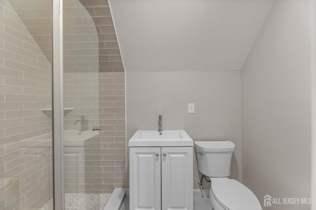 bathroom with toilet, vaulted ceiling, tiled shower, and vanity