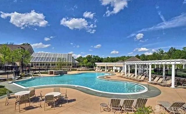 community pool with a patio area, fence, and a pergola