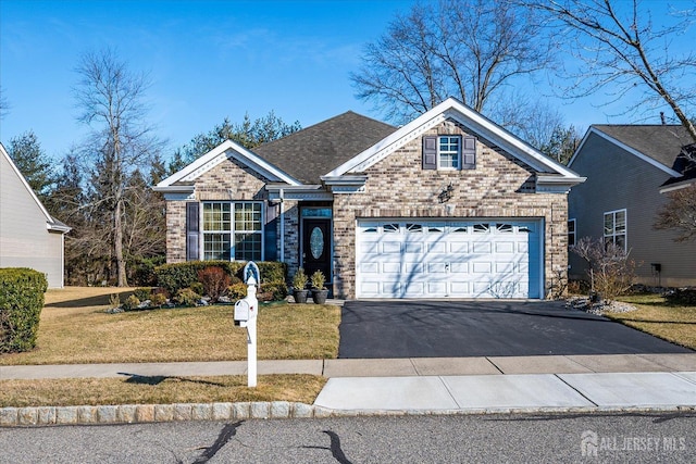 view of front of house with driveway, roof with shingles, an attached garage, a front lawn, and brick siding