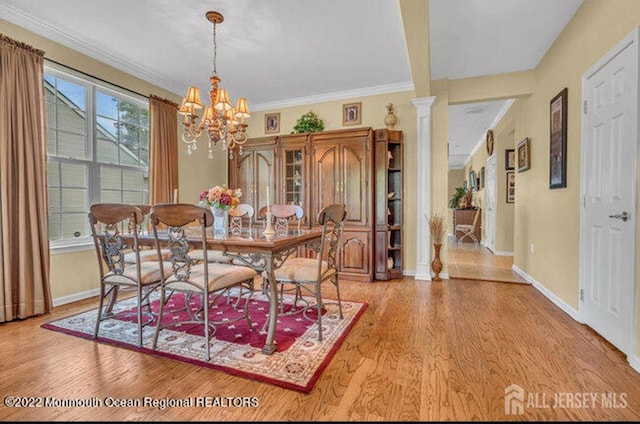 dining area featuring a chandelier, baseboards, ornate columns, and wood finished floors