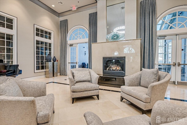 living room with a glass covered fireplace, french doors, a high ceiling, and recessed lighting