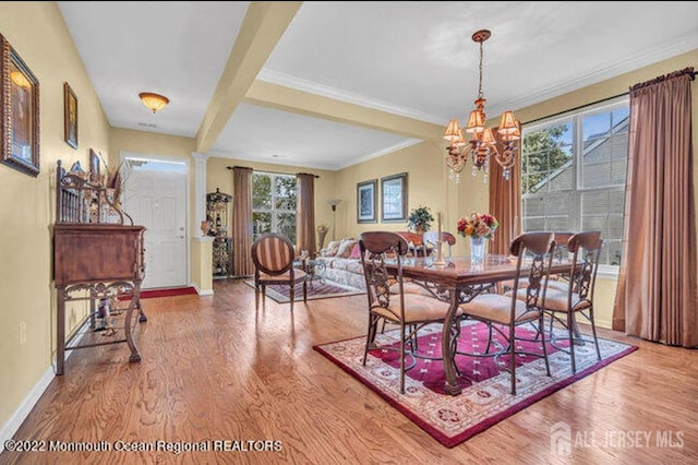 dining area featuring ornate columns, ornamental molding, wood finished floors, a chandelier, and baseboards