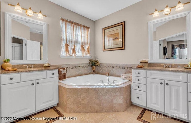 bathroom with a garden tub, a sink, two vanities, and tile patterned flooring