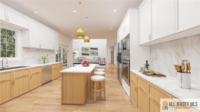 180 River Rd, Monroe, NJ 08831 - kitchen with stainless steel appliances, light wood-style floors, a kitchen island, backsplash, and a breakfast bar area