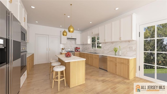 180 River Rd, Monroe, NJ 08831 - kitchen with appliances with stainless steel finishes, light wood-type flooring, backsplash, a breakfast bar, and a center island