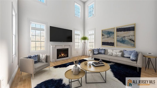 180 River Rd, Monroe, NJ 08831 - living room with wood finished floors, healthy amount of natural light, a lit fireplace, and a high ceiling