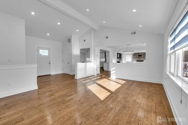 unfurnished living room with beam ceiling, a wealth of natural light, high vaulted ceiling, and hardwood / wood-style flooring