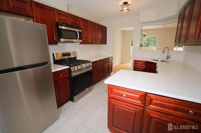 117 Nathan Dr, North Brunswick, NJ 08902 - kitchen featuring appliances with stainless steel finishes, reddish brown cabinets, light countertops, a peninsula, and light tile patterned floors