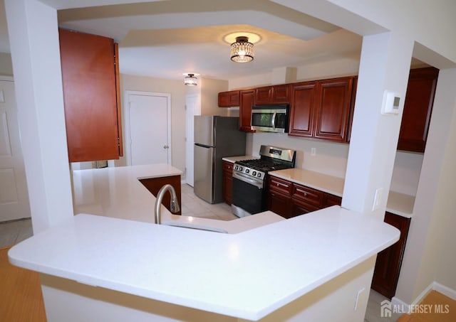 117 Nathan Dr, North Brunswick, NJ 08902 - kitchen with appliances with stainless steel finishes, a peninsula, light countertops, and reddish brown cabinets