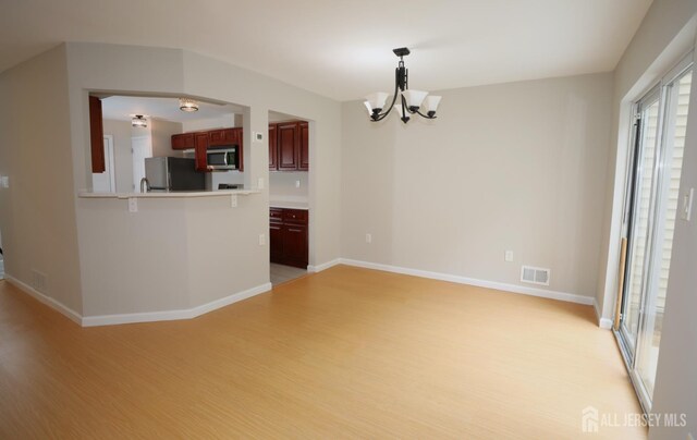 117 Nathan Dr, North Brunswick, NJ 08902 - kitchen with stainless steel microwave, light wood-type flooring, fridge, a chandelier, and dark brown cabinets