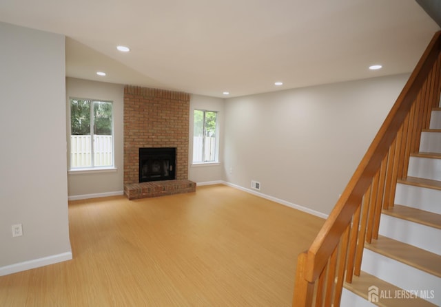117 Nathan Dr, North Brunswick, NJ 08902 - unfurnished living room featuring stairs, light wood-style flooring, recessed lighting, and a brick fireplace