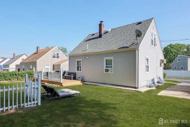 rear view of house featuring a lawn, a chimney, fence, and a deck
