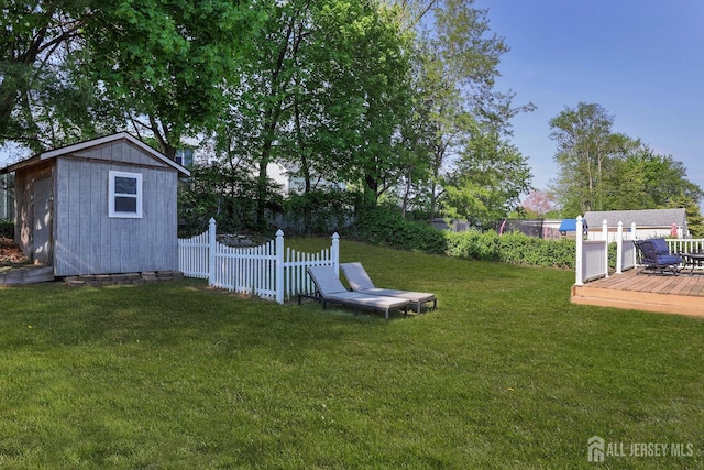 view of yard featuring an outbuilding, fence, a wooden deck, and a storage unit