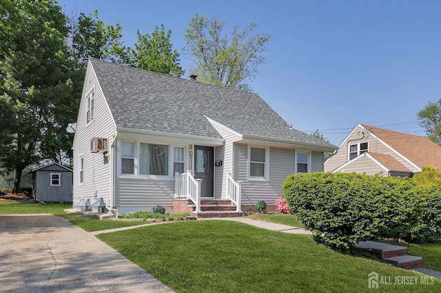view of front of property featuring a front lawn, a shingled roof, and a wall mounted AC