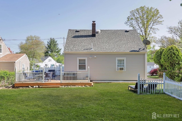 back of house with a lawn, a chimney, fence, a wooden deck, and roof with shingles