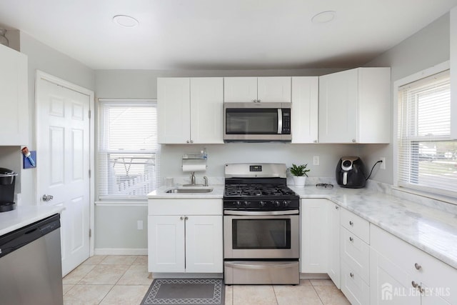 kitchen featuring a sink, light tile patterned flooring, white cabinets, and appliances with stainless steel finishes