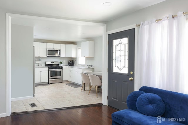 interior space with baseboards, light wood finished floors, and visible vents