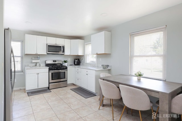 kitchen with white cabinets, light countertops, appliances with stainless steel finishes, and light tile patterned flooring