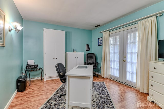 office with light hardwood / wood-style flooring and french doors