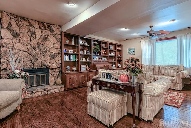 living room featuring dark hardwood / wood-style flooring, a fireplace, and ceiling fan