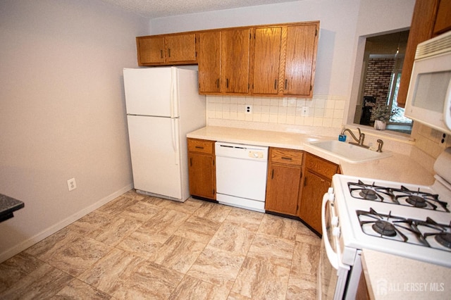 kitchen featuring brown cabinetry, a sink, white appliances, and light countertops