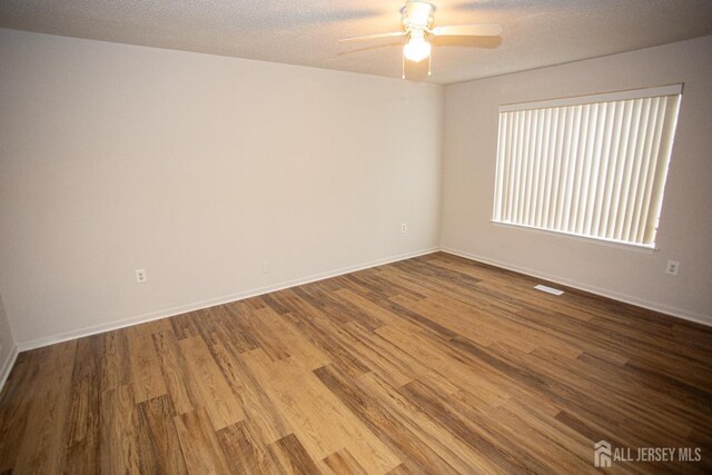 spare room featuring baseboards, wood finished floors, a textured ceiling, and ceiling fan