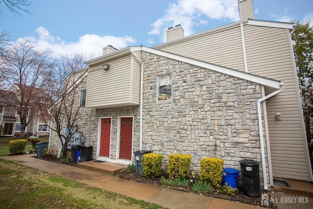 exterior space with stone siding and a chimney