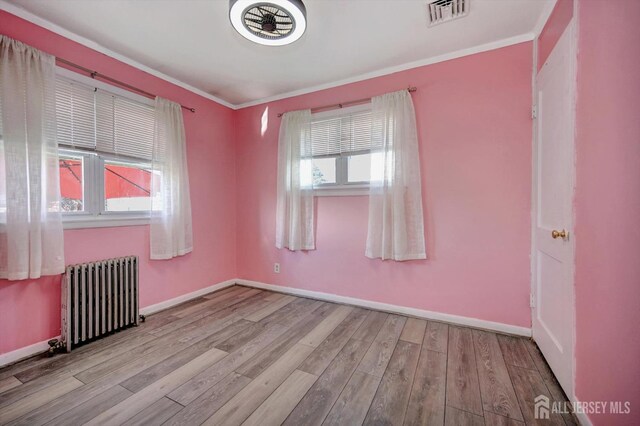 unfurnished room with radiator, light hardwood / wood-style floors, and ornamental molding