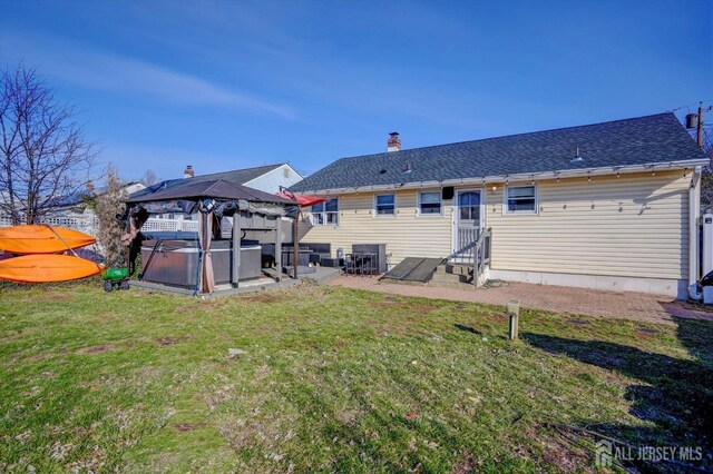 rear view of property with a gazebo, a yard, and a hot tub