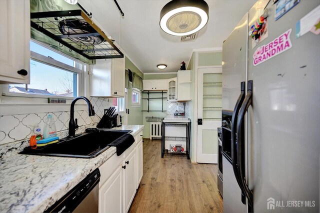 kitchen with radiator, stainless steel appliances, sink, light hardwood / wood-style floors, and white cabinetry