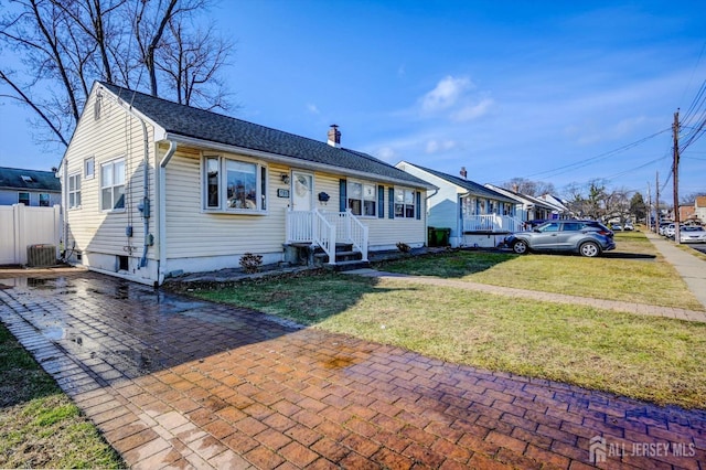 view of front of house with central AC and a front lawn