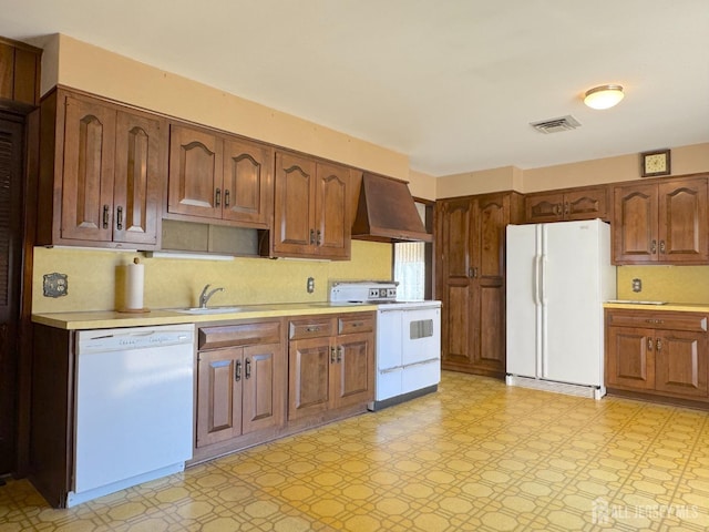 kitchen with white appliances, ventilation hood, light countertops, and light floors