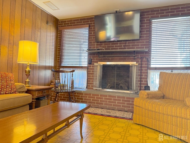 living area featuring wooden walls, tile patterned floors, and a brick fireplace