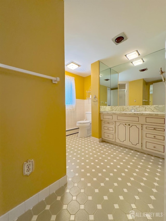 bathroom with baseboard heating, toilet, vanity, and baseboards