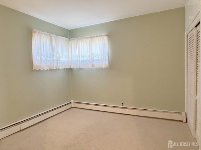 carpeted empty room with a baseboard heating unit