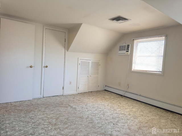 additional living space with a baseboard heating unit, carpet flooring, lofted ceiling, and an AC wall unit