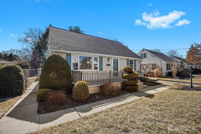 view of front of house with a front yard, a gate, and a shingled roof