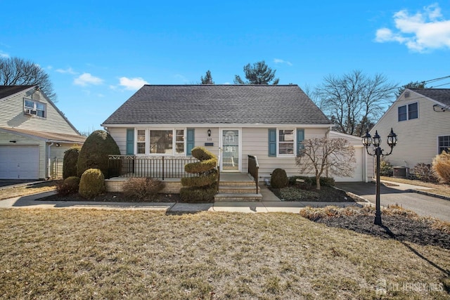 view of front facade with cooling unit, driveway, a front lawn, and roof with shingles