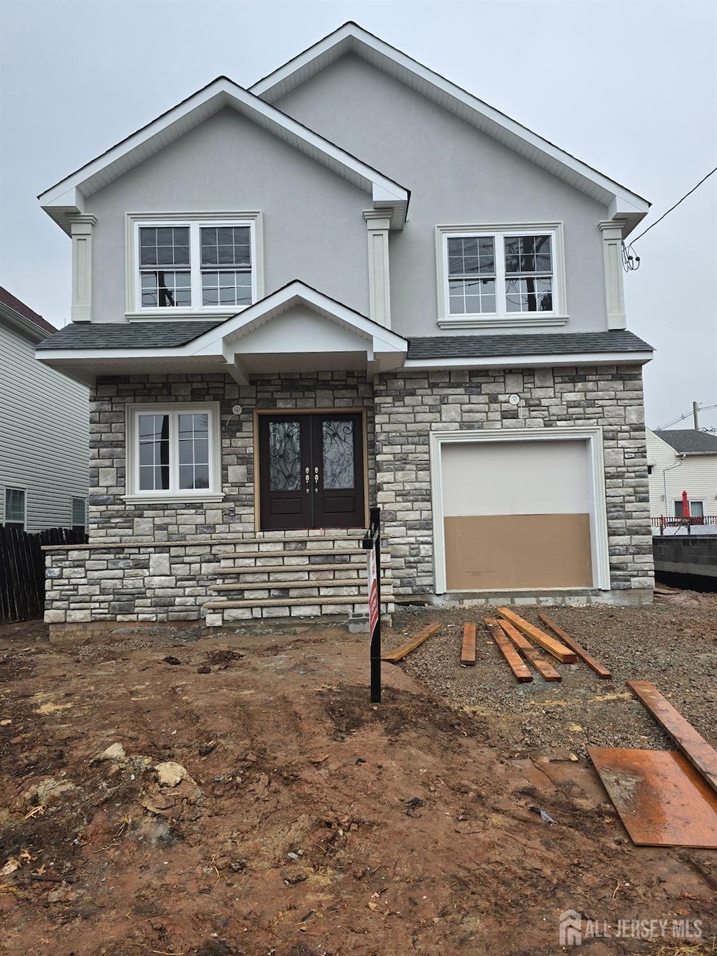 traditional-style home featuring stone siding, an attached garage, and stucco siding