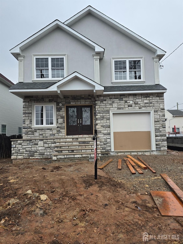 traditional-style home featuring stone siding, an attached garage, and stucco siding