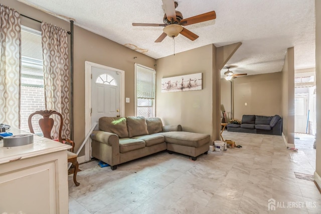 living room with a wealth of natural light, ceiling fan, and a textured ceiling